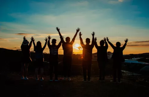Group Of People With Arms Raised Facing Horizon