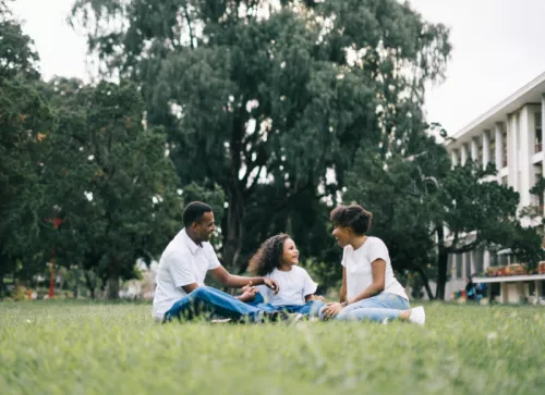 Family Sitting On A Lawn In Front Of House