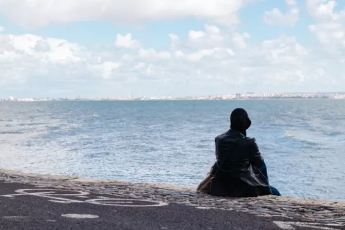 Muslim woman sitting by coast