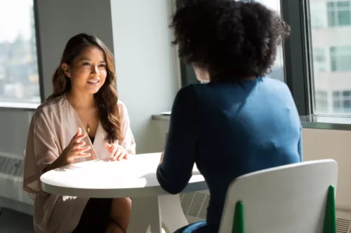 Two women talking over table
