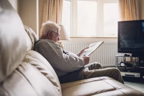 Man sitting on sofa reading paper