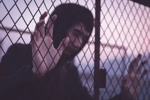 Asian man leaning on cage