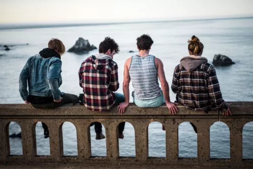 Four young people sitting on bridge