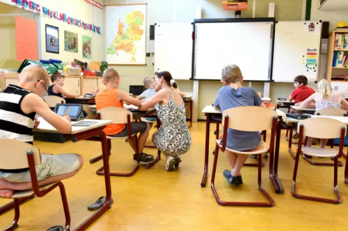 children sitting on brown chairs inside the classroom